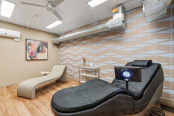A room with a black massage chair and a white bench.